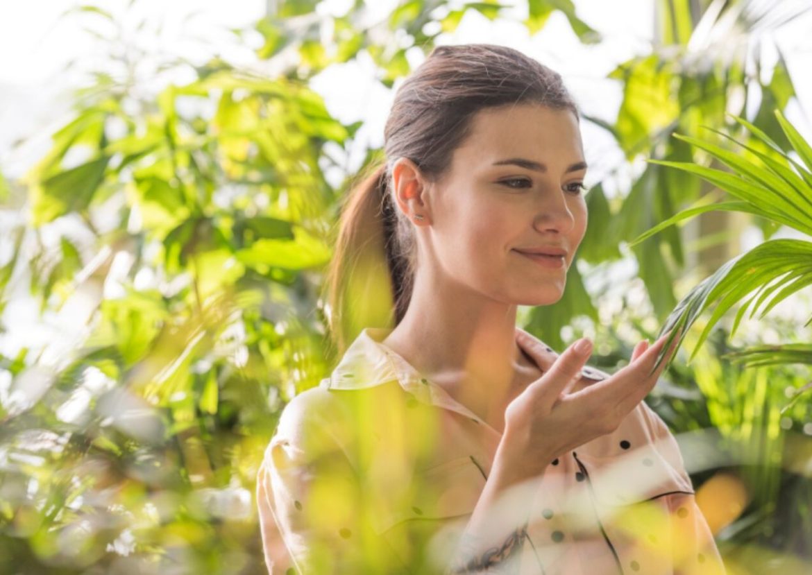 Harmonie et bien-être avec la santé naturelle. Femme souriante au milieu de plantes vertes, évoquant la santé naturelle.