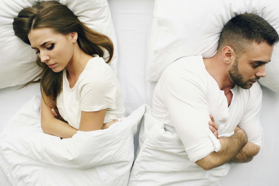 Couple couché dos à dos avec les bras croisés, reflétant le besoin de surmonter le désir inversé.   